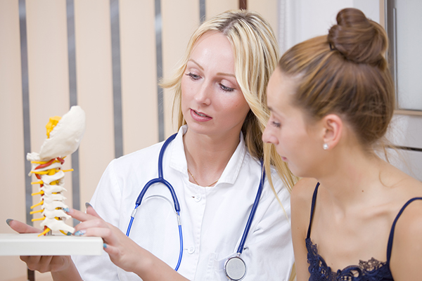 woman doctor showing patient spine bones in office