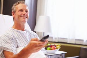 Male Patient In Hospital Bed Watching Television Male Patient In Hospital Bed Watching Television