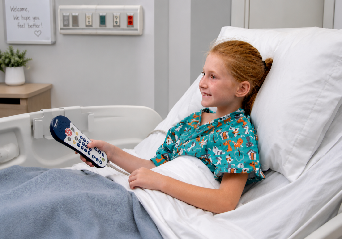 Young patient in a hospital bed holding a healthcare pillow speaker remote for TV and room controls.