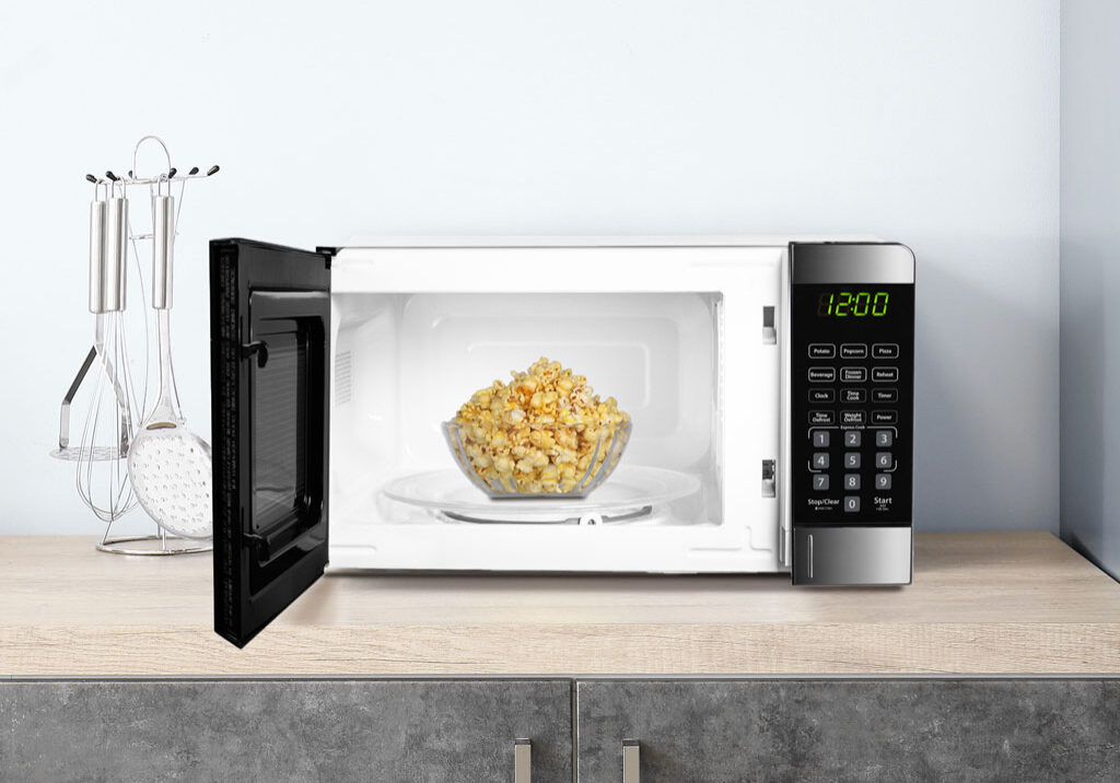 Hotel guest using a Danby® microwave in a comfortable guest room.
