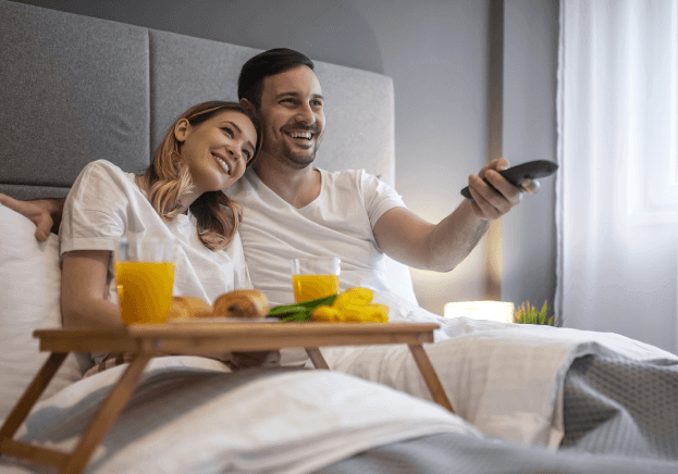 guests watching tv in their hotel room with remote
